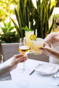 Guests raising cocktails and wine at Avra Beverly Hills restaurant in Los Angeles