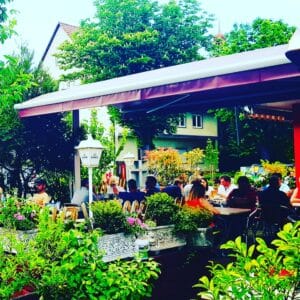 Outdoor restaurant seating surrounded by greenery at Corfu