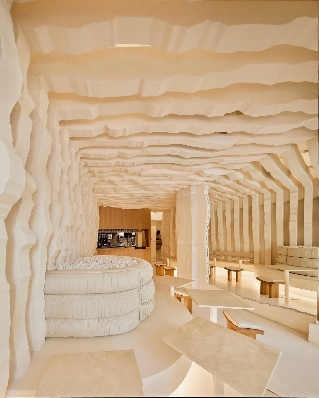 Contemporary cream-toned interior with sculpted walls and seating at Egeo