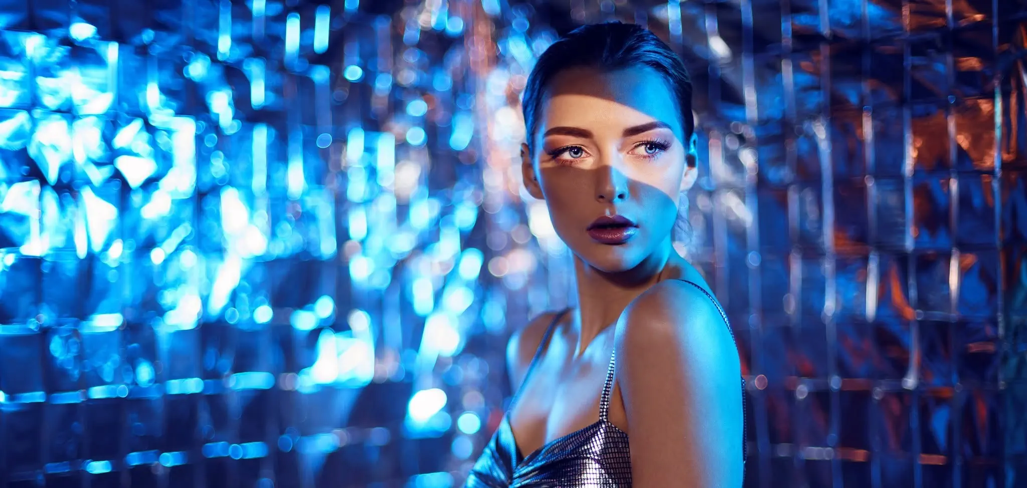 Stylised fashion portrait with blue lighting and reflective geometric background