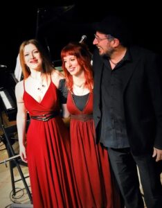 Three members of Aerikón standing together beside a piano after a musical performance in Rome, Italy