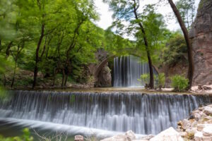 Stone bridge and waterfall surrounded by forest in the Trikala area of Thessaly, Greece